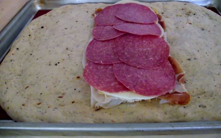 Stuffing the stromboli dough with cold cuts and cheese.