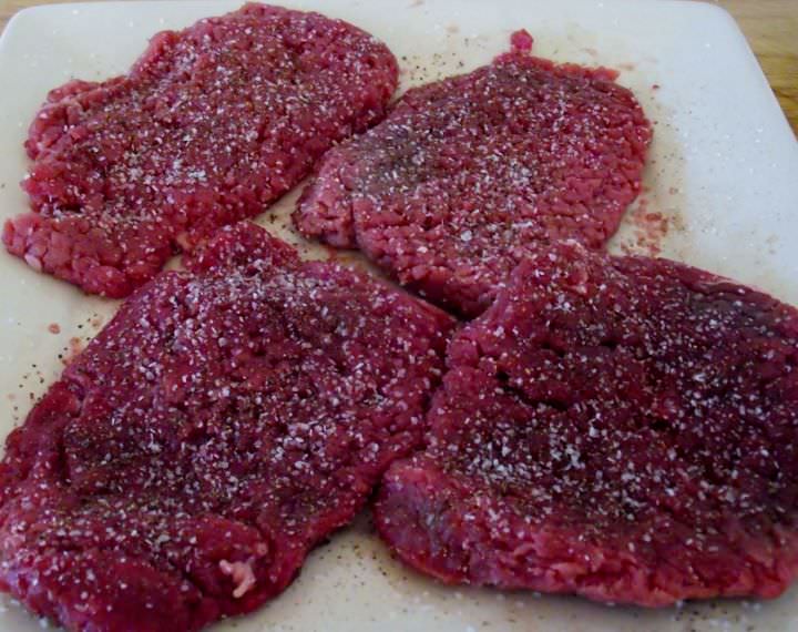 Tenderized round steak or cube steak, seasoned with salt and pepper and resting on a plate.