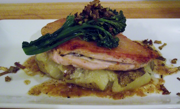 Chicken under a brick, smashed potato, and broccoli rabe on a plate.