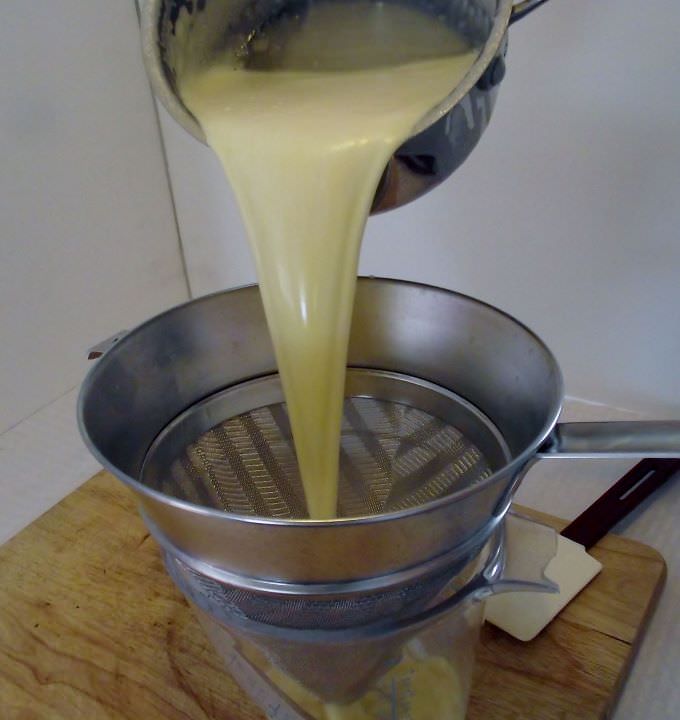 Straining the creme brulee base through a chinois.