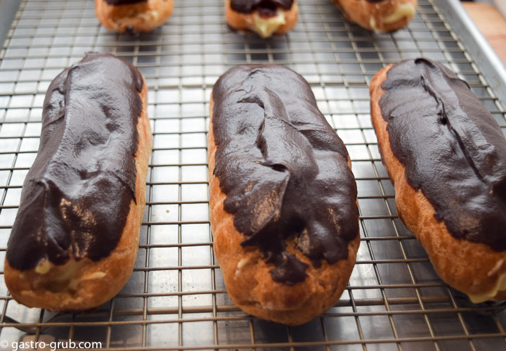 Chocolate eclairs on a wire rack.