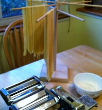 Homemade fettuccine hanging on a pasta rack.