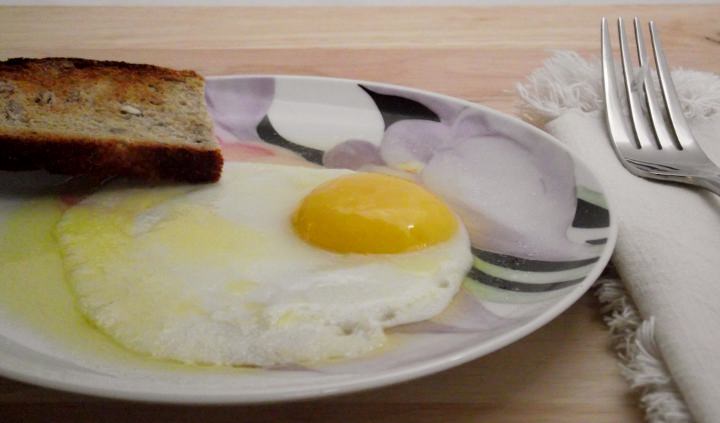 A fried egg with toast and butter.