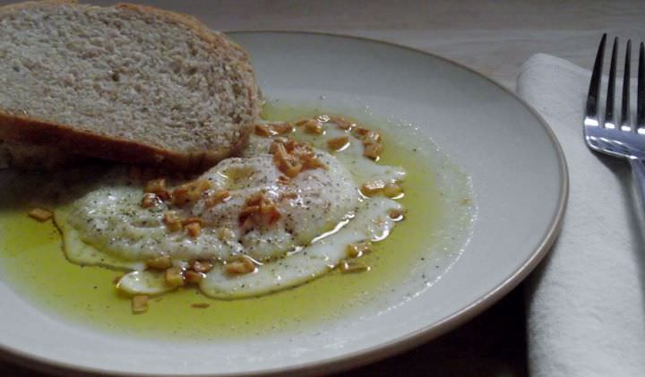 Garlic fried egg with olive oil and bread.