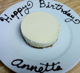 Cheesecake with happy birthday, Annette written in chocolate, on the plate.