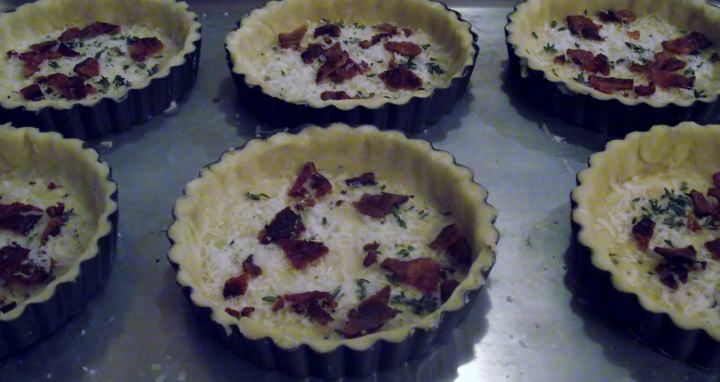 Individual tart pans with pastry, cheese, bacon, and thyme.