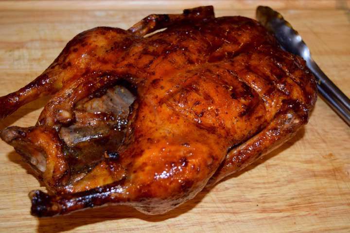 Whole roasted duck on a cutting board.