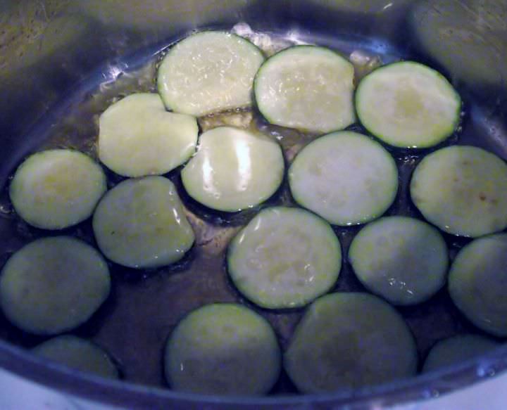 Zucchini frying in a pot.