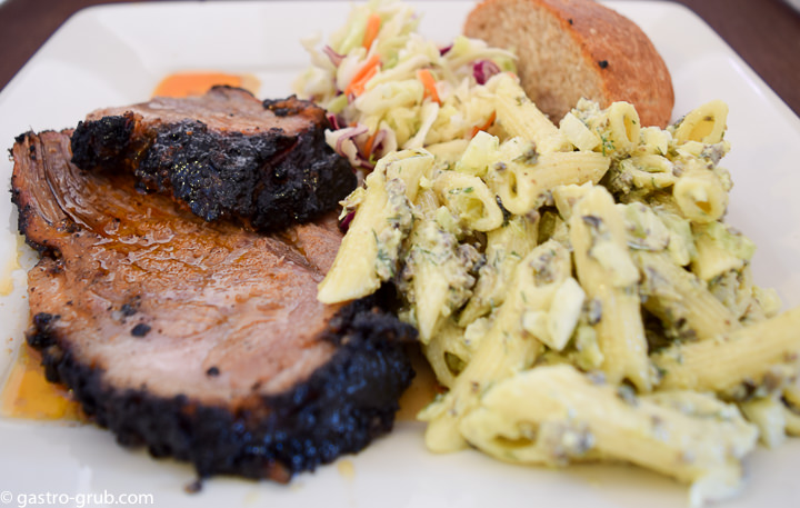 Smoked brisket, macaroni salad, cole slaw and sweet rolls on a plate.