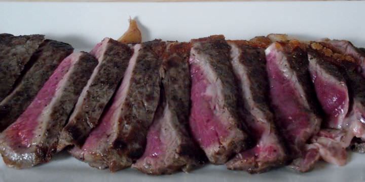 Rare NY Strip Steak: sliced on a bias and fanned out on a plate.