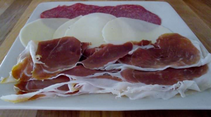 Prosciutto, provolone and salami on a plate.