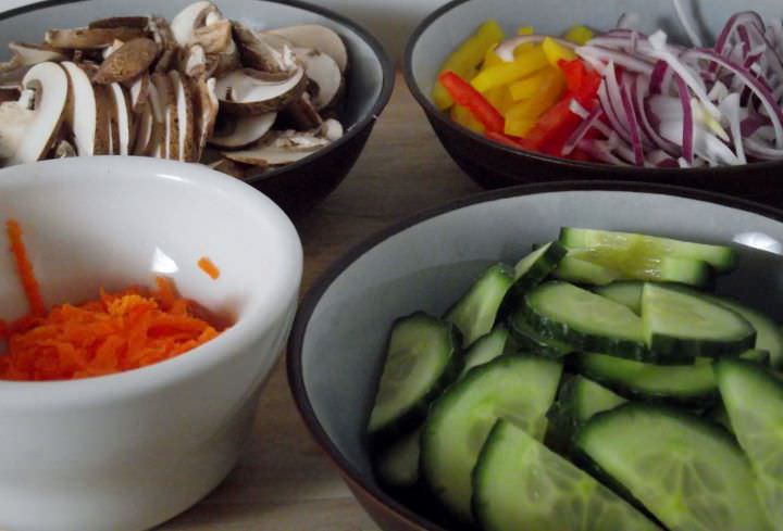 Sliced vegetables for the salad: mushrooms, carrots, red onions, and red and yellow peppers.