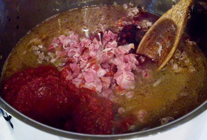 Adding the prosciutto, the tomato puree and the wine and mix well. Add the milk, little by little until it is completely absorbed.