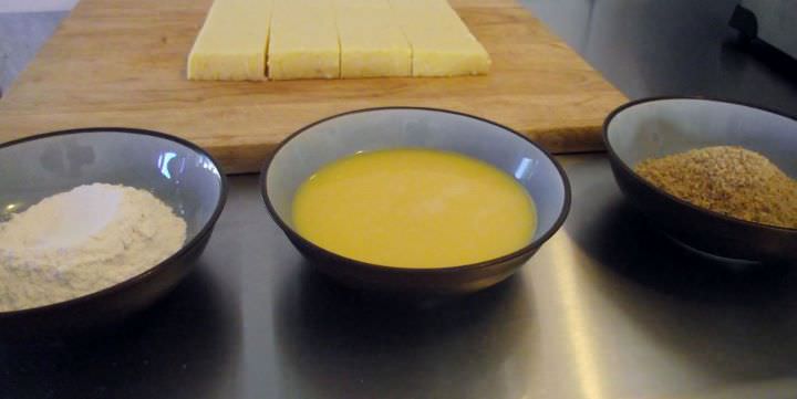 Preparing to bread polenta squares, with flour, egg, and breadcrumbs.