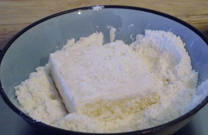 Polenta square being dredged in flour.