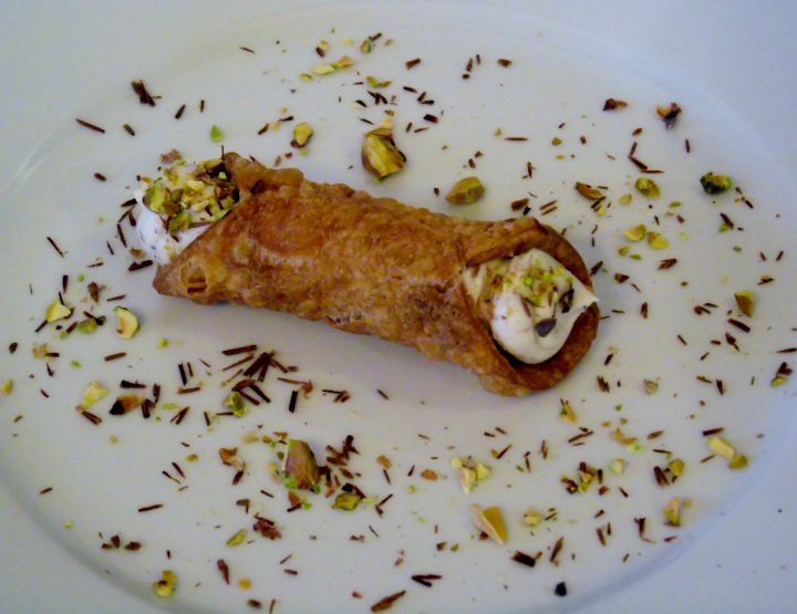 Cannoli on a plate with chocolate shavings and pistachios.