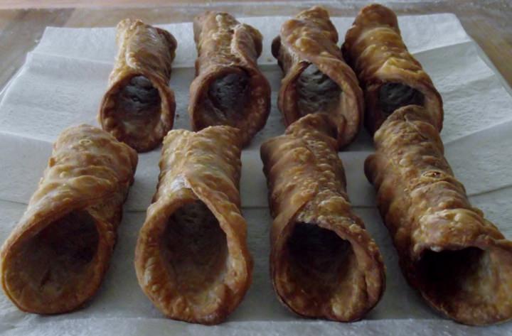 Fried cannoli shells resting on paper towels.