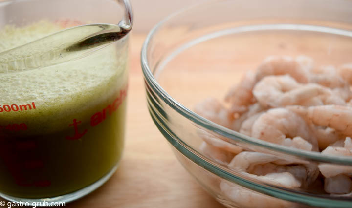 Ceviche sauce in a measuring cup and shrimp in a bowl.