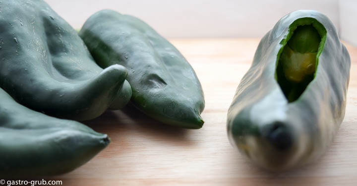 Poblano chilies on a cutting board showing the opening for stuffing the chili.