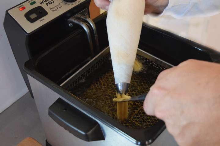 Transfer the choux dough into a pastry bag fitted with a star tip. Pipe the dough into a preheated deep fryer cutting the dough off at your desired length.