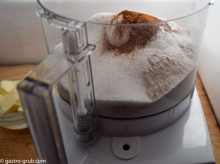 Mixing the flour, sugar, baking powder, baking soda, salt, and cinnamon in the bowl of a food processor.