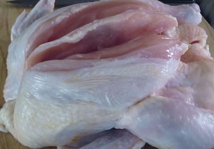 Removing the breasts from a whole chicken.