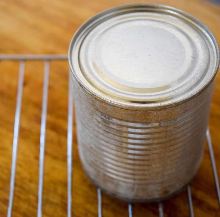 Dulce de leche cooling in the can on a rack.