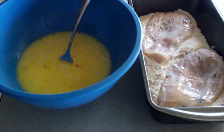 Dredging chicken breasts in flour.