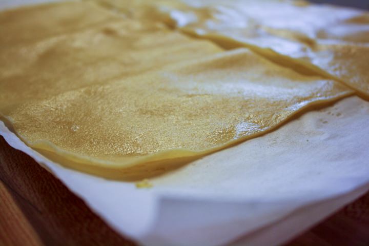 Cooked pasta sheets drying on a tea towel.