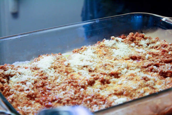 Building the lasagna by layering with sauce, pasta and cheese.