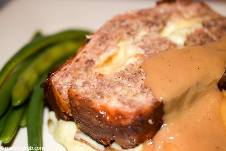 Stuffed meatloaf with mashed potatoes, brown gravy, and green beans.