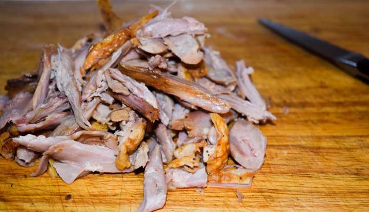 Pulled duck meat on a cutting board.