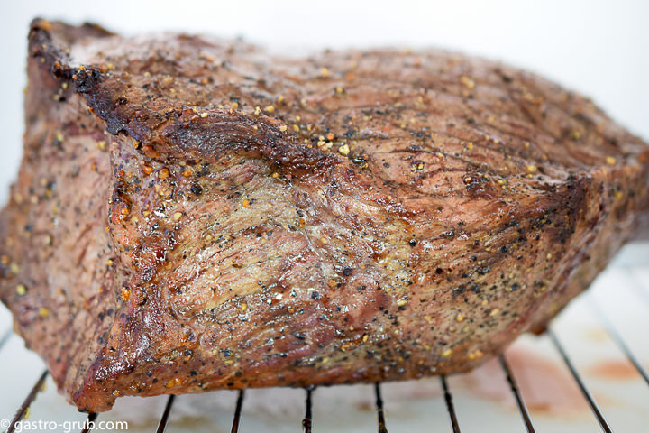 Roast beef cooling on a rack.