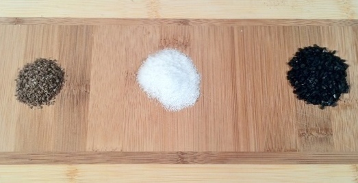 Image of smoked salt, kosher salt, and lava salt on a wooden cheese board.