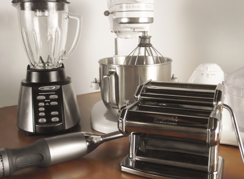 Kitchen appliances: blender, stand mixer, pasta machine, food processor, and a stick blender.