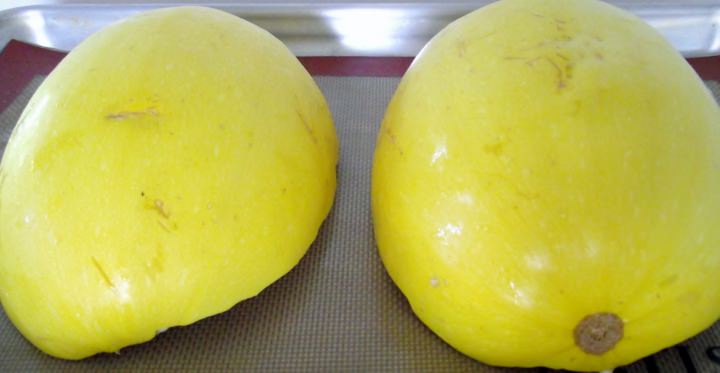 Squash halves cut side down on a sheet pan lined with a silicone baking mat.