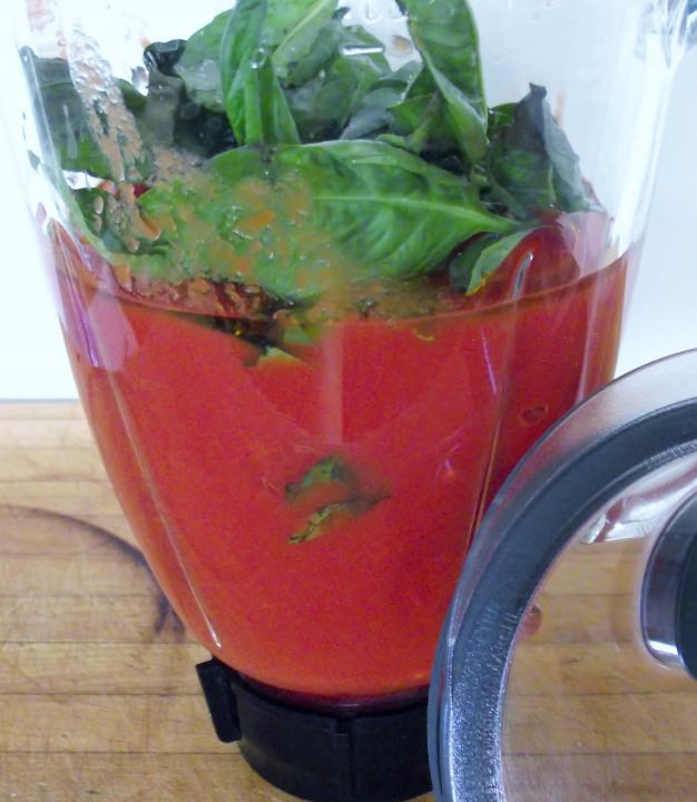 The tomatoes, olive oil, kosher salt, and sweet basil in a blender bowl.