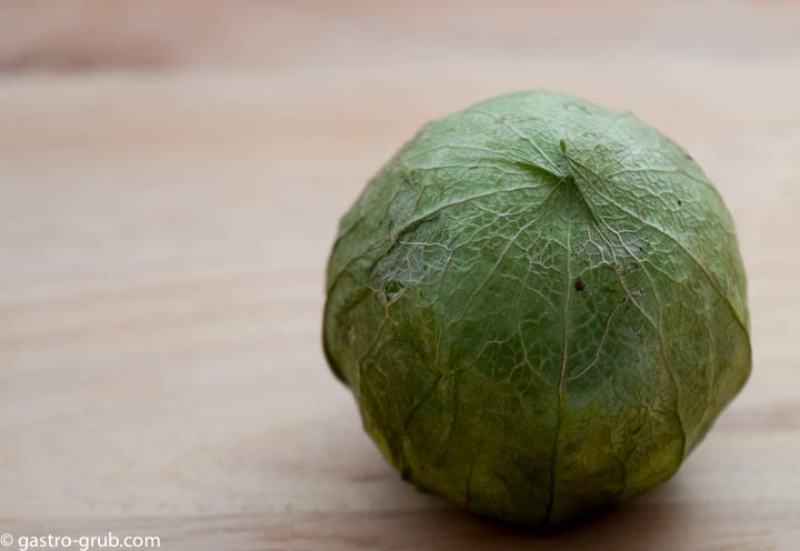 A tomatillo on a cutting board.