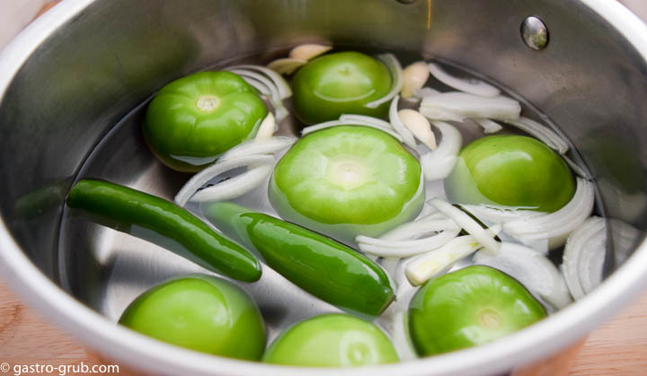 Ingredients for tomatillo sauce in a pot with water.