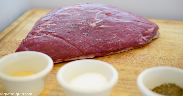 Tri tip on a cutting board ready to be cured with salt, pepper and garlic powder.