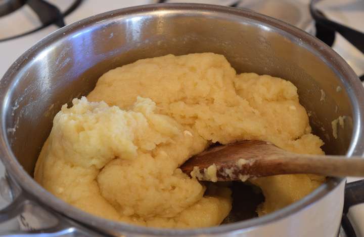 When the water milk mixture comes to a boil dump all the flour in at once. Immediately stir rapidly until the dough pulls away from the sides of the pot and forms into a ball.