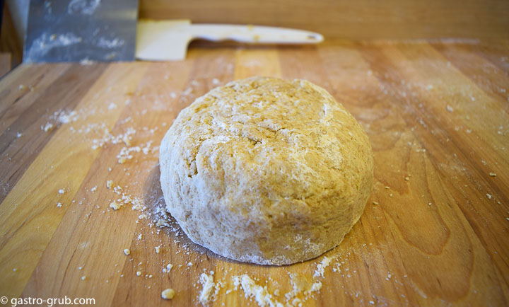 Pie dough formed into a disc, on the cutting board.