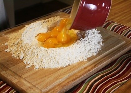 Adding eggs to flour for pasta.