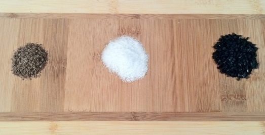 Image of smoked salt, kosher salt, and lava salt on a wooden cheese board.