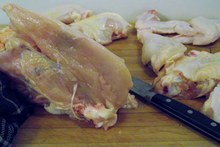 The chicken carcass and chicken pieces on the cutting board.