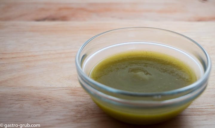 Tomatillo sauce in a glass bowl on a cutting board.